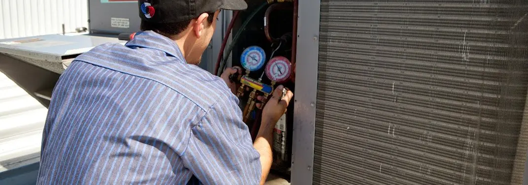 HVAC technician servicing a condenser unit in Bay City